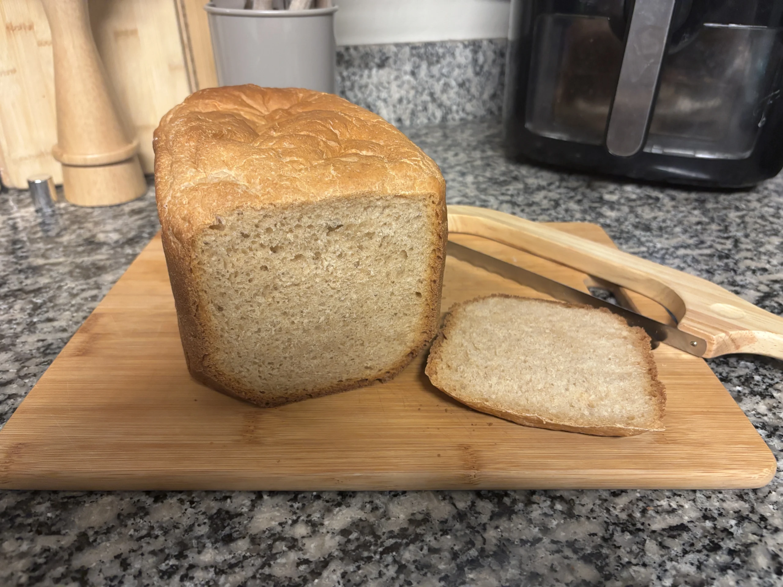 Soft homemade bread slice showing fluffy interior crumb next to full loaf on cutting board