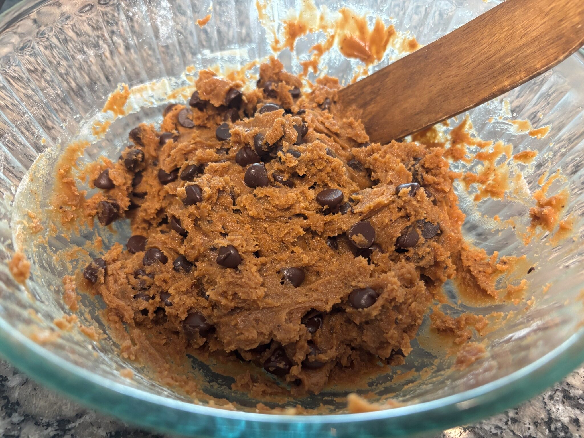 Coconut sugar chocolate chip cookie dough mixed with chocolate chips in a glass bowl