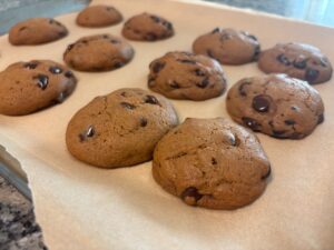 Fresh baked brown butter chocolate chip cookies cooling on a parchment-lined baking sheet
