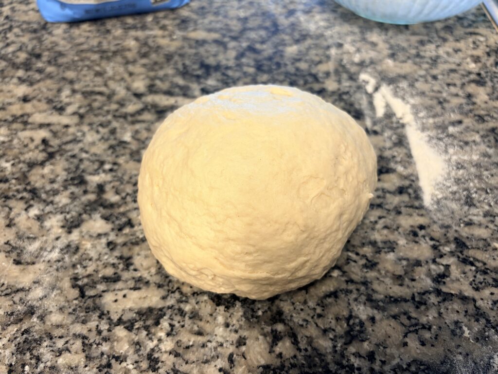 Smooth ball of kneaded white bread dough ready for the first rise.