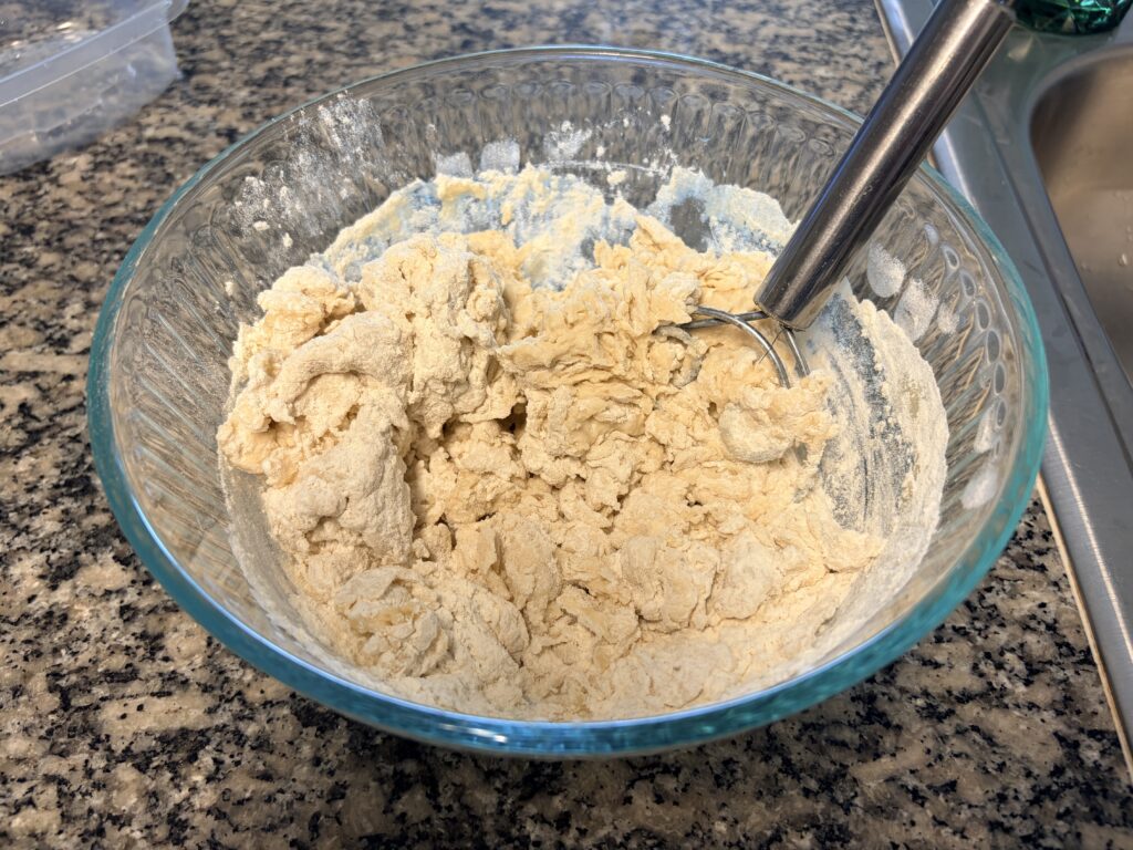 Homemade bread dough being mixed with flour before kneading.
