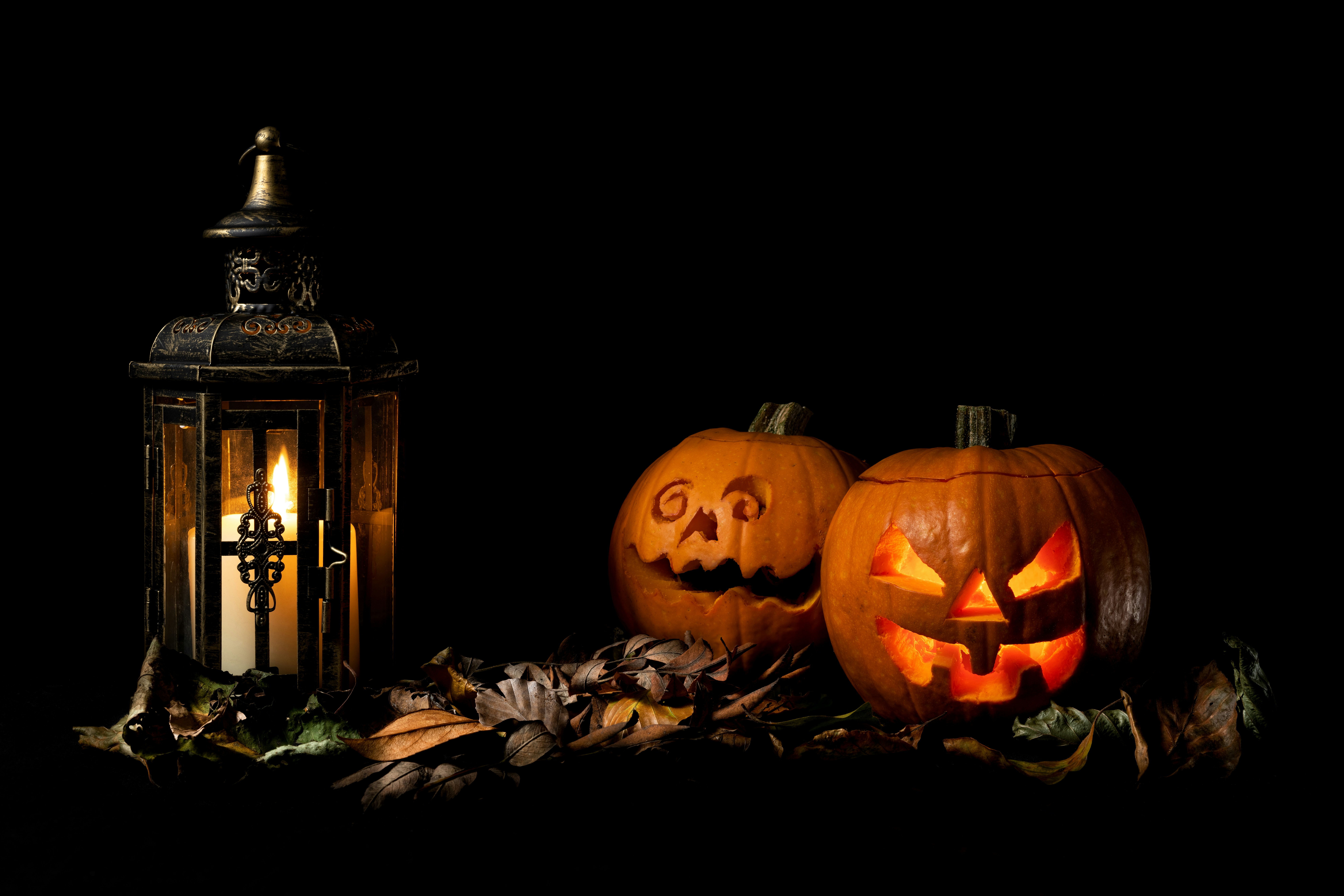 Two carved Halloween pumpkins beside a glowing metal lantern