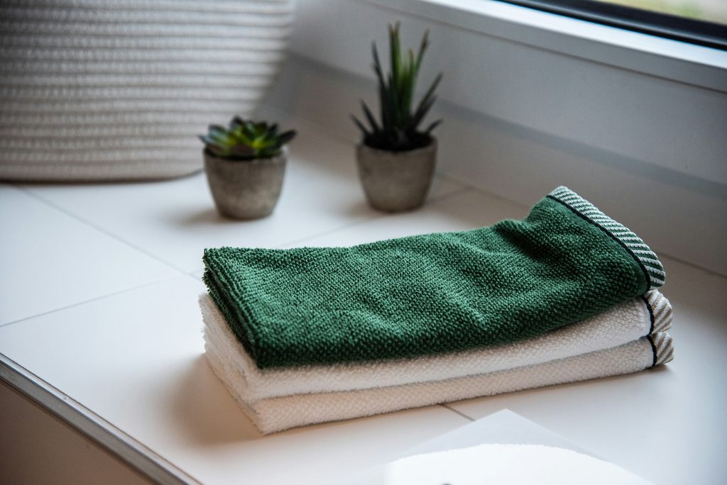 White and green bath towels folded and stacked neatly